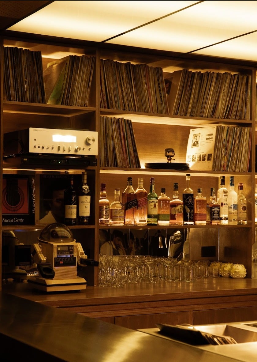 Estantería de vinilos y equipo de sonido sobre la barra de madera, 55DB, Medellín