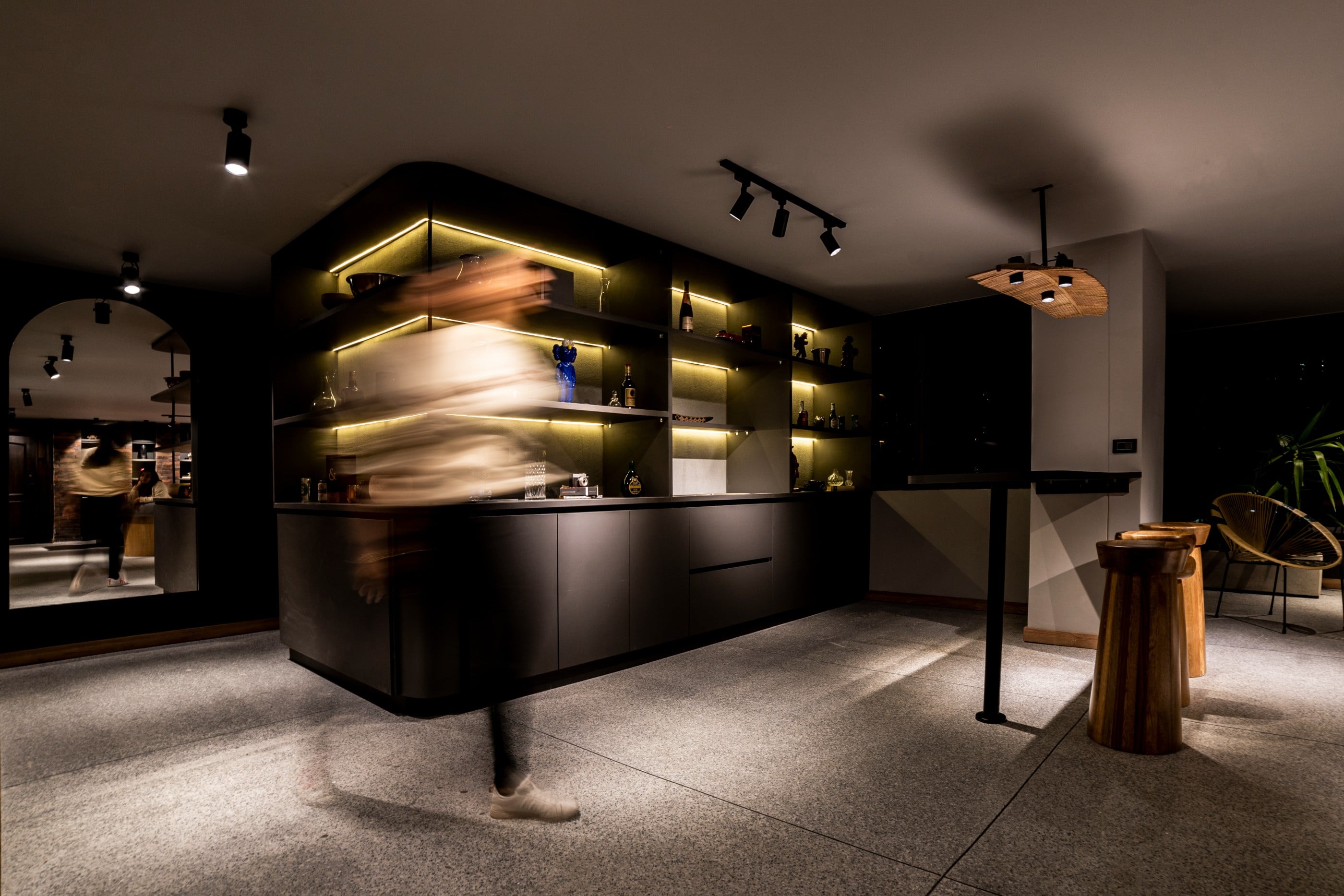 Bar en casa con estantería iluminada y butacos torneados en madera, La Almenara, Medellín