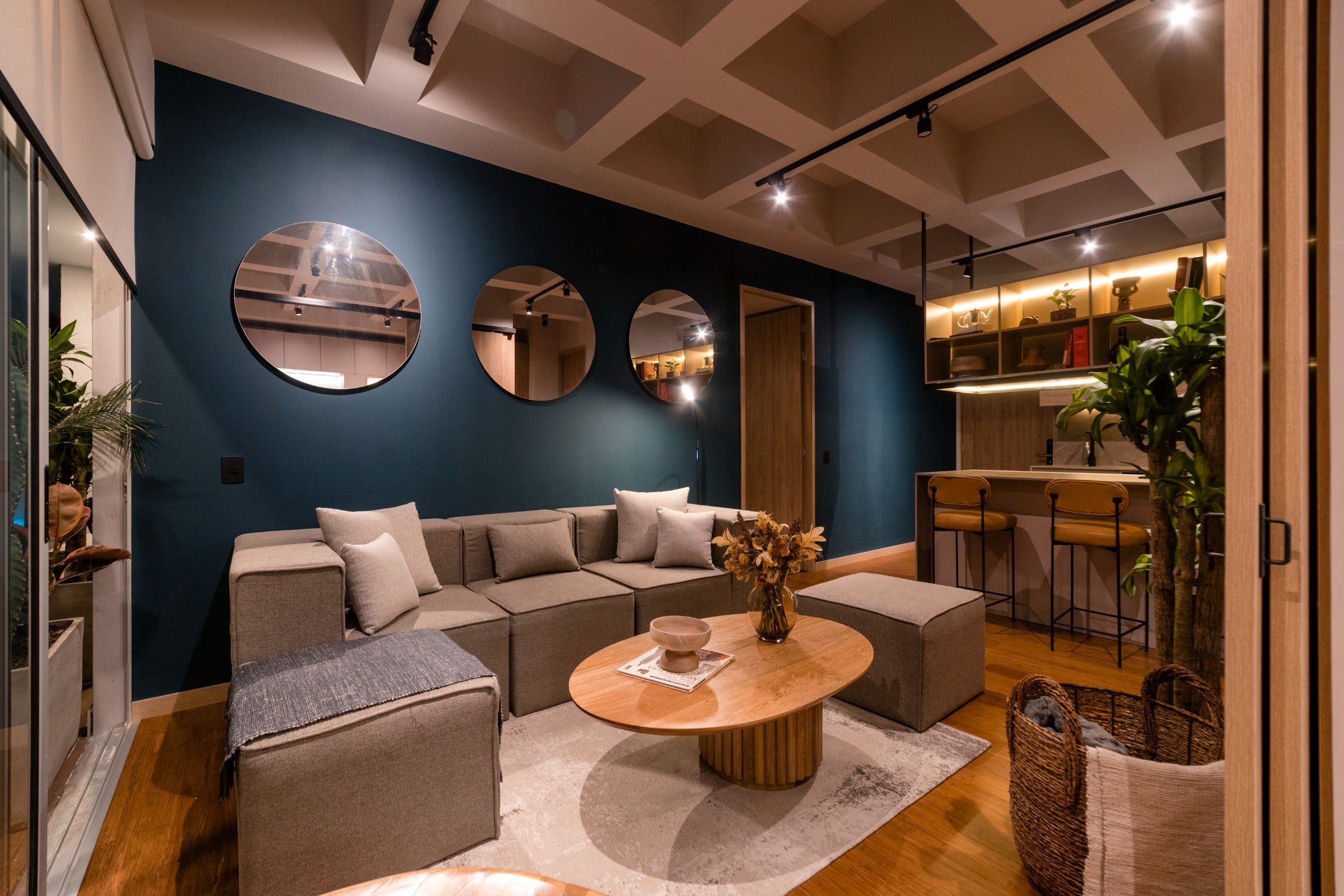 Sala con muro azul petróleo, espejos redondos y sofá gris, Campestre 402