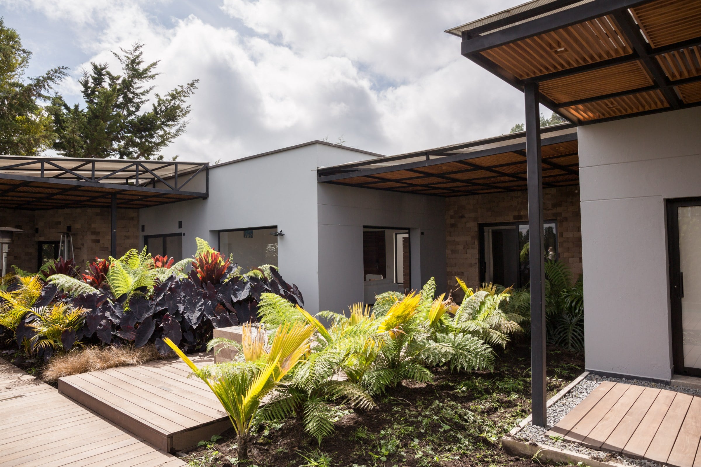 Patio con pérgola metálica y jardín, Casa 64