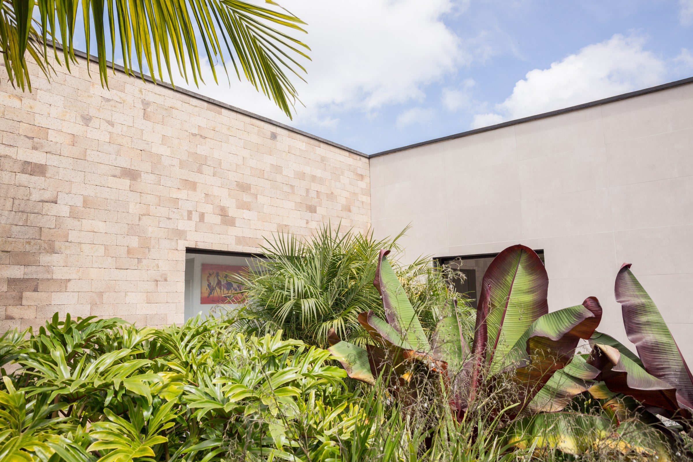 Jardín tropical contra la fachada en bloque calizo, Casa 64