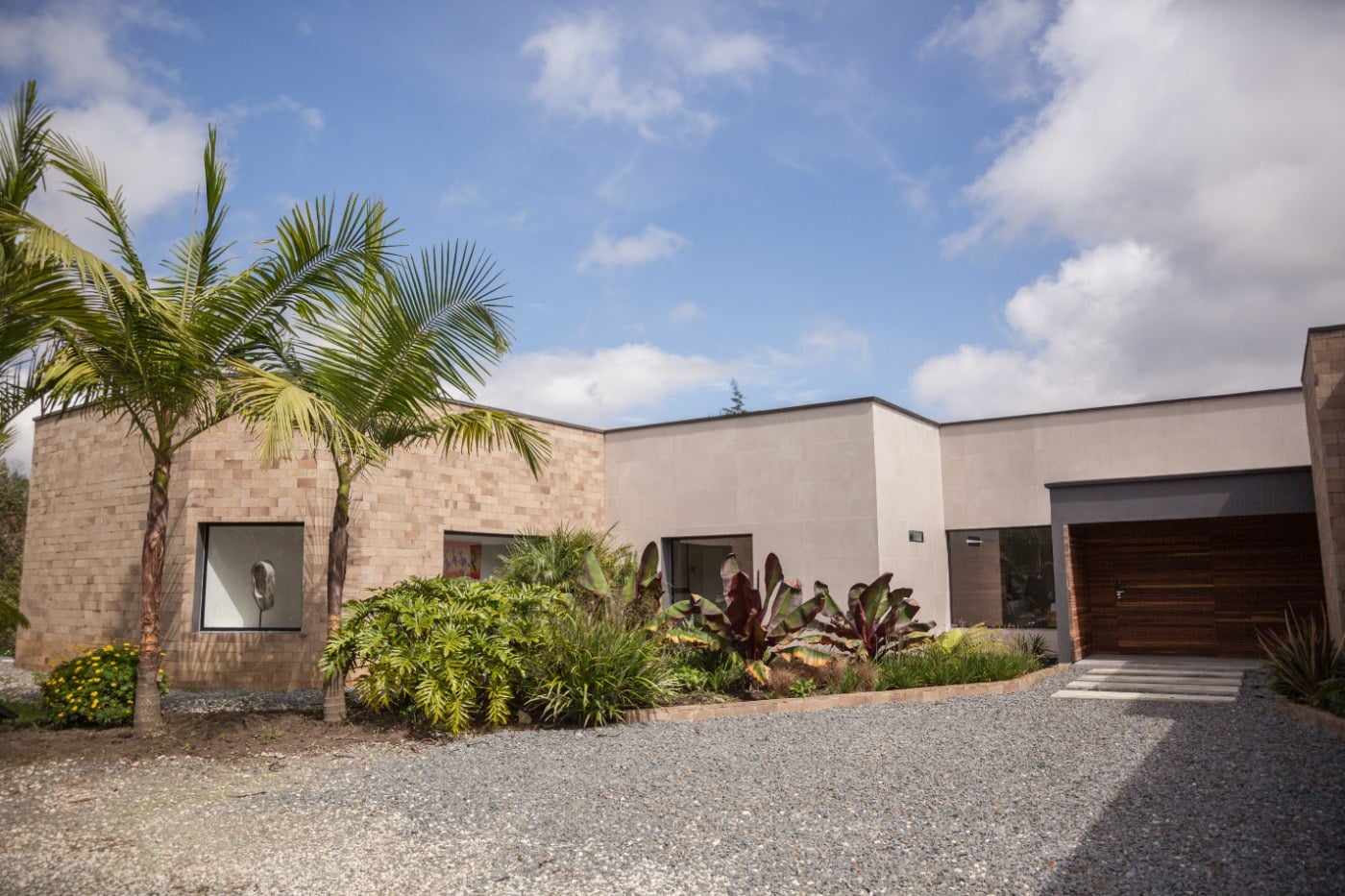 Fachada en bloque de piedra y muros blancos con jardín tropical, Casa 64, El Retiro