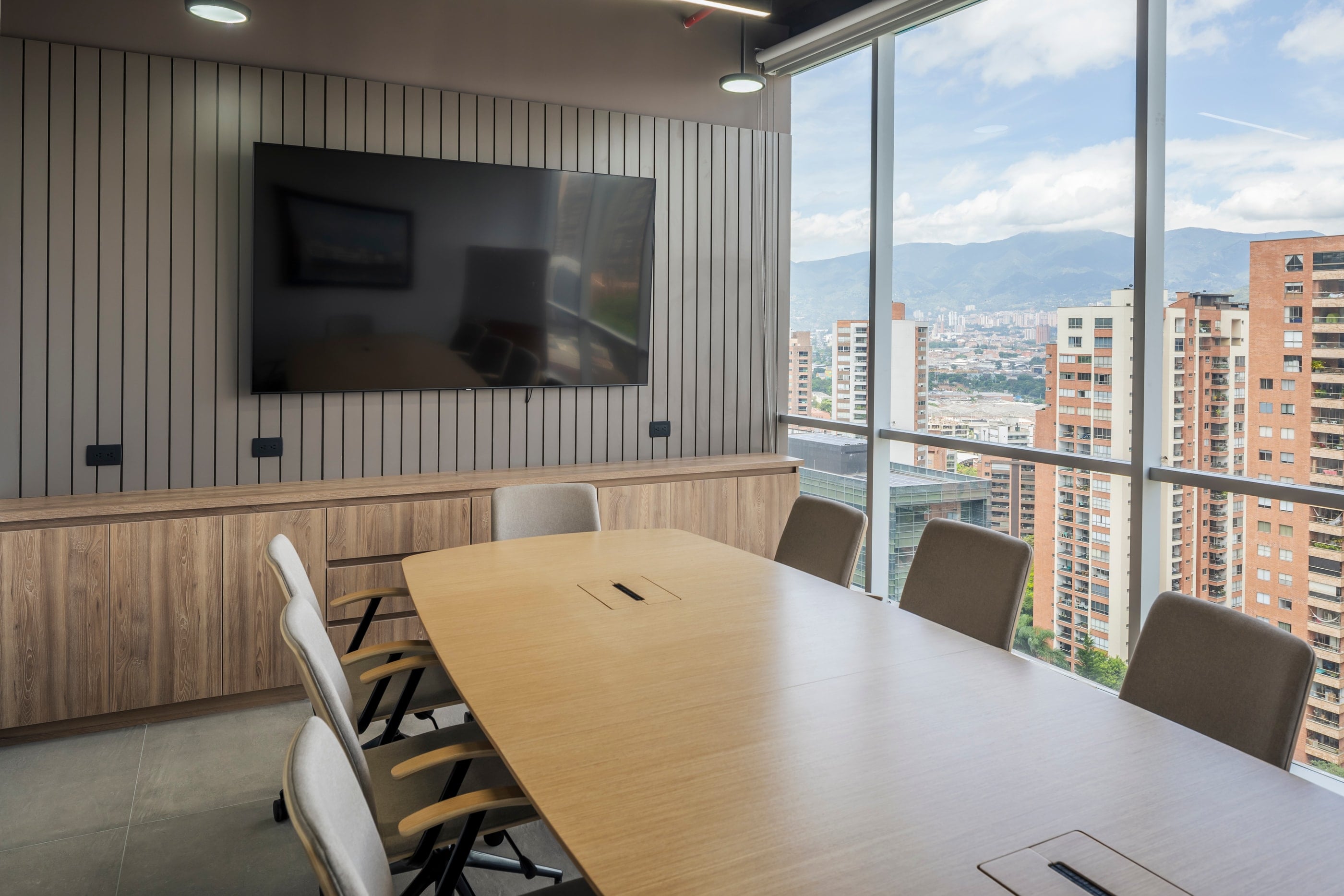 Sala de juntas con mesa en madera y ventanal hacia la ciudad, CrearCimientos