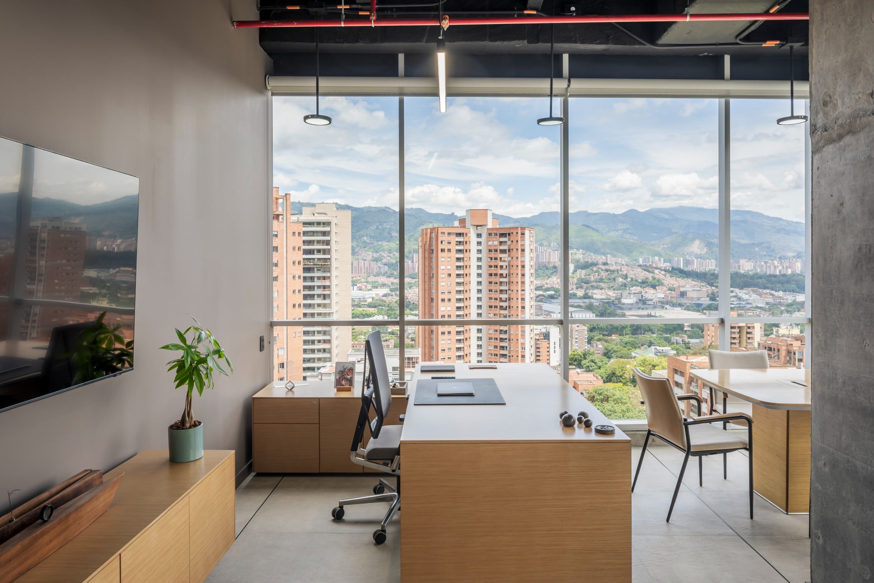 Oficina con escritorio en madera y vista panorámica de Medellín, oficinas CrearCimientos
